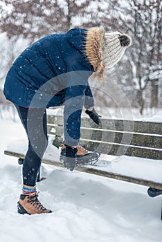 Woman putting non slip snow cleats on boots for winter hike