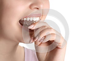 Woman putting occlusal splint in mouth on white background, closeup