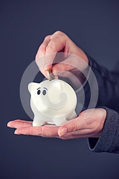 Woman putting one euro coin in piggy bank