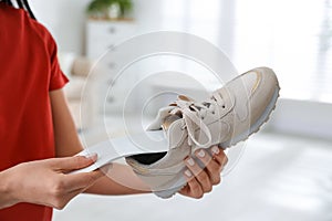 Woman putting orthopedic insole into shoe at home