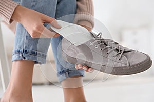 Woman putting orthopedic insole into shoe at home