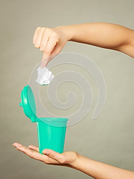 Woman putting paper into small trash can