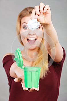 Woman putting paper into small trash can