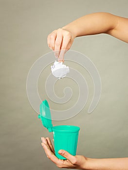 Woman putting paper into small trash can