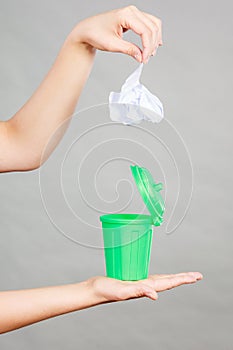 Woman putting paper into small trash can