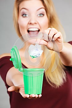 Woman putting paper into small trash can