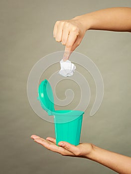 Woman putting paper into small trash can