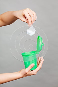 Woman putting paper into small trash can