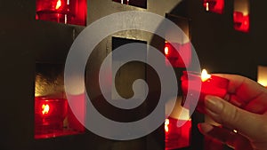 Woman putting Red Praying Candle in the Wall with other Candles. Red Wish and Pray Candles in a Catholic Church Video