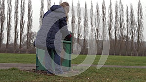 Woman putting rubbish in park bin