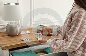 Woman putting scented sachet into drawer with clothes, closeup