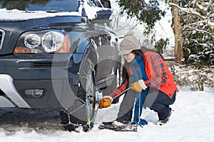 Woman Putting Snow Chains Onto Tyre Of Car