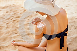 Woman putting sunblock lotion on shoulder before tanning during summer holiday on beach. Sun cream. Suntan.