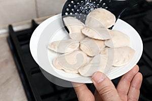 Woman putting tasty dumplings (varenyky) onto plate, closeup