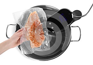 Woman putting vacuum packed meat into pot with sous vide cooker on white background, top view. Thermal immersion circulator