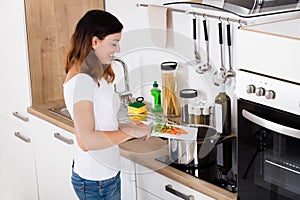 Woman Putting Vegetables In Utensil