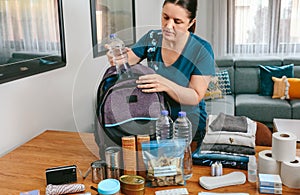 Woman putting a water bottle to prepare emergency backpack