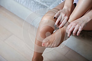 Woman putting on white nylon stockings