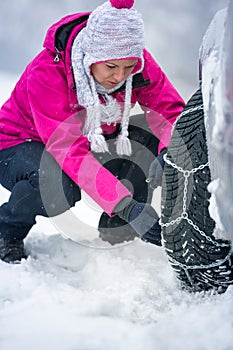 Woman putting winter chains on car