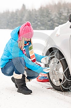 Woman putting winter tire chains car wheel