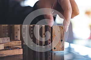 A woman putting wooden domino game in order on table