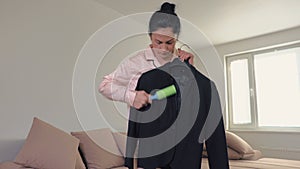 Woman in pyjama cleaning clothes with lint roller