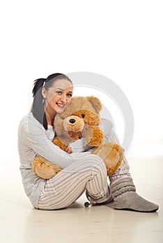 Woman in pyjama hugging bear