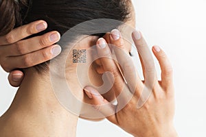 Woman with QR code behind ear. Future technology chipization. Pandemic control