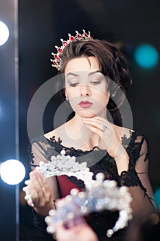 Woman, queen with crown, looks in mirror. Luxury, fashion