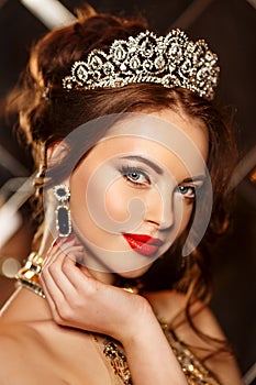 Woman queen princess in crown and lux dress, lights party background Luxury girl Long shiny healthy volume hair Waves Curls