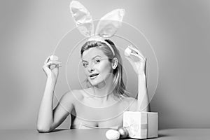 Woman with rabbit ears hold easter egg over pink background.