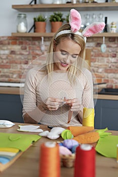 Woman in a rabbit`s ears sews Easter decorations