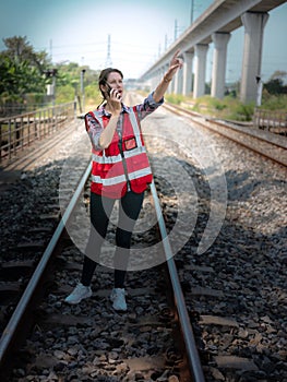 Woman railway engineer use walkie-talkie talking in to talk to maintenance department at site work of train garage