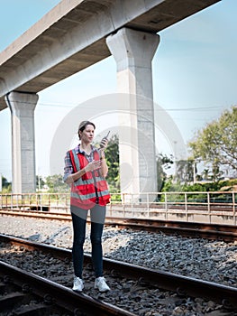 Woman railway engineer use walkie-talkie talking in to talk to maintenance department at site work of train garage