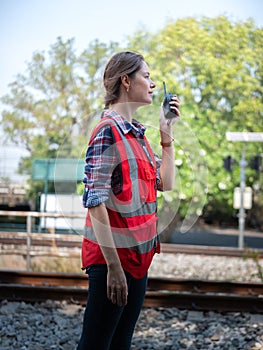 Woman railway engineer use walkie-talkie talking in to talk to maintenance department at site work of train garage