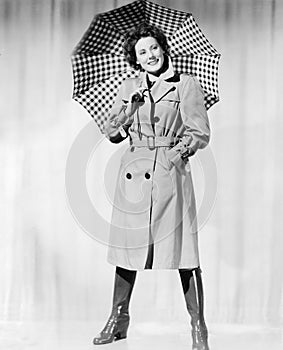 Woman in rain gear holding an umbrella and smiling photo