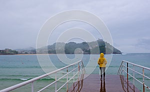 Woman in the rain on a jetty in the city of Donostia-San Sebastian.