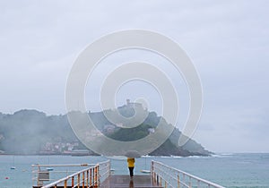 Woman in the rain on a jetty in the city of Donostia-San Sebastian.