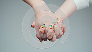 Woman with rainbow manicure holding hand with other woman