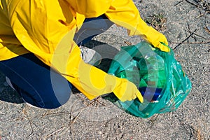 Woman in raincoat picking up trash in park