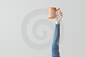 Woman raised arm up holding coffee cup