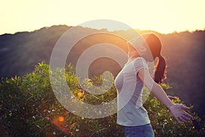 woman raised arms to sunrise on mountain top in the moring photo
