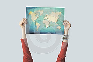 Woman raised up hand holding world map photo