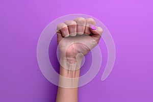 A woman raises a purple fist for International Women\'s Day