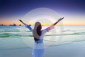 Woman raising arms to sunrise