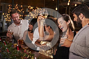 Woman raising a glass at a Christmas party in a bar