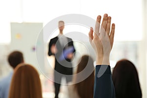 Woman raising hand to ask question at business training indoors, closeup