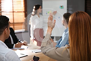 Woman raising hand to ask question at seminar in office