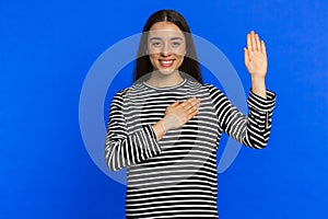 Woman raising hand to take oath, promising to be honest and to tell truth, keeping hand on chest