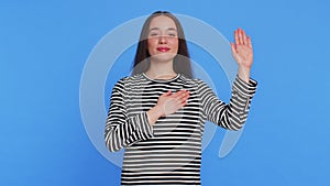 Woman raising hand to take oath, promising to be honest and to tell truth, keeping hand on chest